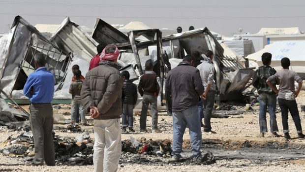 Syrští uprchlíci stojí nedaleko zničeného majetku v uprchlickém táboře Zaatarí
