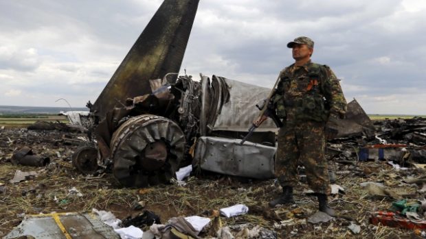 Ozbrojený ruský separatista hlídá místo dopadu ukrajinského vojenského Iljušinu, který rebelové sestřelili u Luhansku