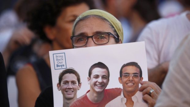 Žena drží fotografii tří izraelských mladíků