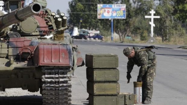 Ukrajinský technik nakládá munici do tanku na kontrolním stanovišti u města Mariupol