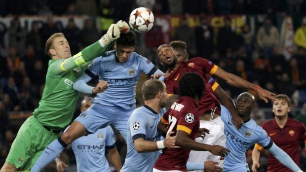 Kapitán fotbalistů Manchesteru City Joe Hart vyboxovává míč před dotírajícími protihráči