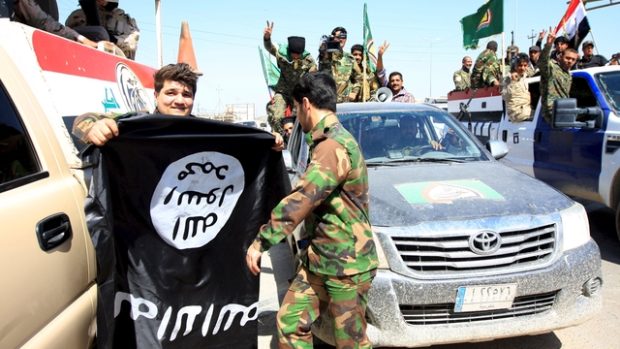Šíitští bojovníci s vlajkou Islámského státu, kterou strhli v Tikrítu