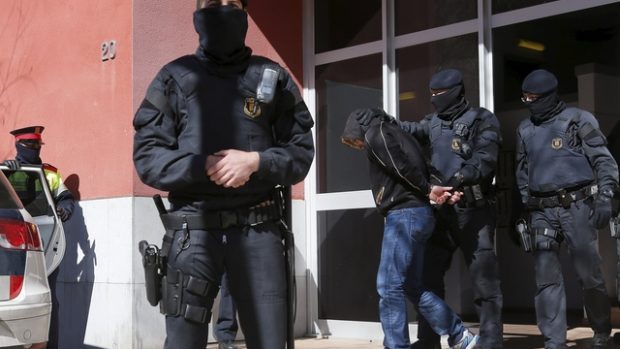 Katalánská policie odvádí jednoho ze zadržených při razii proti islamistům
