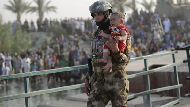 Irácký voják odnáší dítě z Ramádí nedaleko Bagdádu (19. května 2015)