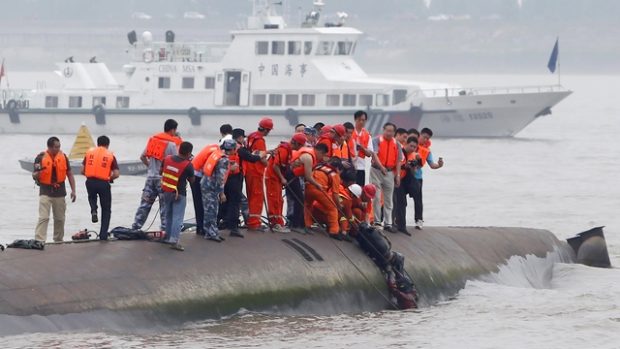 Záchranáři pomáhají pasažérům, kteří byli uvezněni v trupu lodi