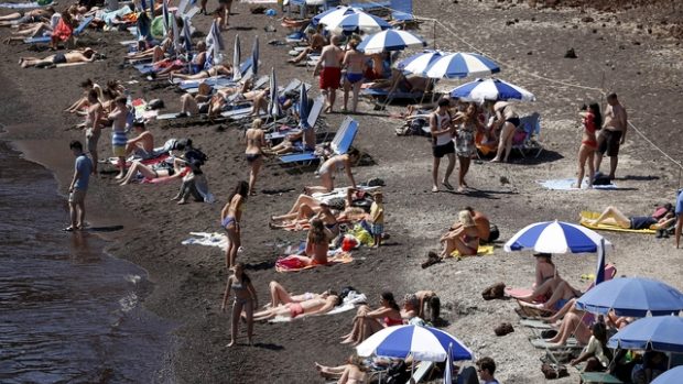 Lidé se opalují u moře na jednom z řeckých ostrovů Santorini
