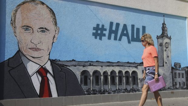 Žena v krymském Simferomolu prochází kolem graffiti, které znázorňuje ruského prezidenta Vladimira Putina