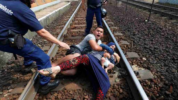 Maďarská policie s uprchlíky, kteří se snaží utéct z nádraží v Bicske