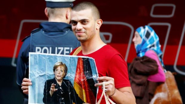 Uprchlík s portrétem německé kancléřky Angely Merkelová po příjezdu na nádraží v Mnichově