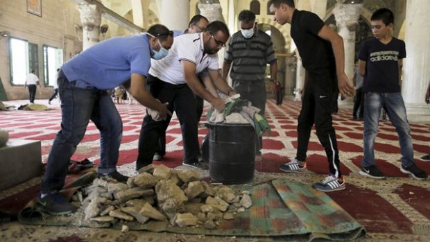 Palestinci sbírají kameny, které zůstaly v mešitě Al-Aksá po střetech s izraelskou policií
