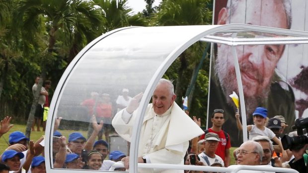 Papež František projíždí ve svém voze ulicemi Havany. V pozadí za ním bilboard s portrétem bývalého vůdce Kuby Fidela Castra
