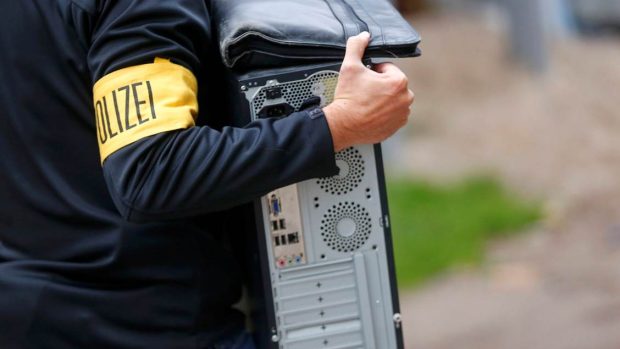 Německý policista odnáší počítač zabavený při razii v Berlíně. Policie hledala důkazy o verbování bojovníků do Sýrie