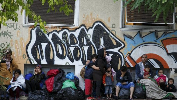 Migranti v centru Atén se snaží ukrýt před deštěm