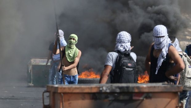 Maskovaní Palestinci při střetech s izraelskými vojáky blízko židovské osady Bet El v blízkosti Ramalláhu (12. 10. 2015)