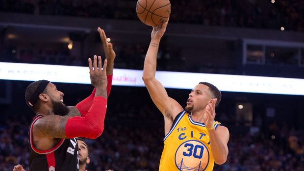 Hvězda Golden State Warriors Stephen Curry zakončuje přes obránce v zápase proti Toronto Raptors