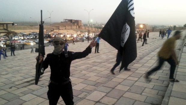 Bojovník IS drží jeho vlajku v ulicích Mosulu (archivní foto)