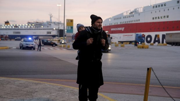 Migrant s děckem po příjezdu do aténského přístavu v Pireu