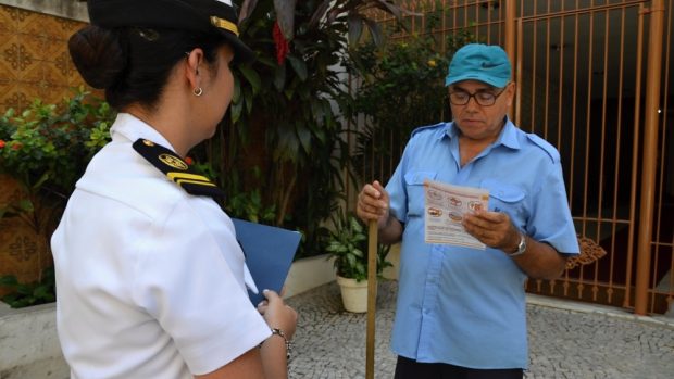 Nadporučice brazilské armády předává portýrovi ve čtvrti Vila Isabel leták a informace, jak proti komárům