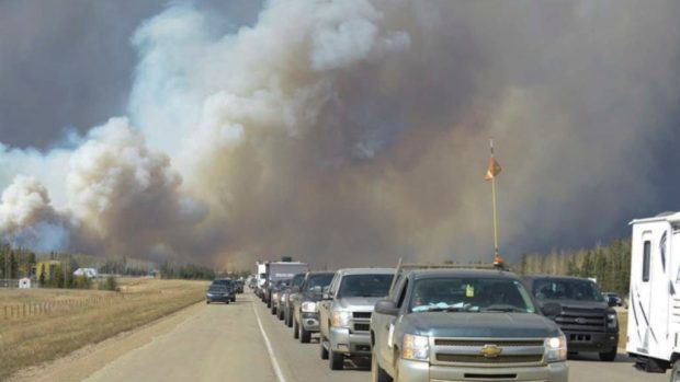 Obyvatelé města Fort McMurray prchají před lesním požárem