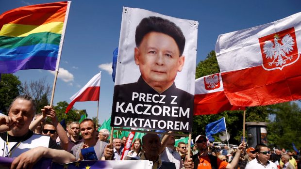Protivládní demonstrace ve Varšavě. Muž drží plakát, na němž je lídr strany Právo a spravedlnost  Jaroslaw Kaczynski vyobrazený tak, že připomíná severokorejského diktátora Kim Čong-una