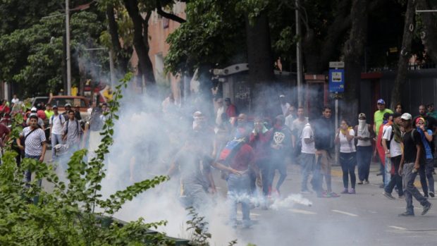 Stoupenci opozice utíkají před slzným plynem, který použila venezuelská policie k potlačení protivládní demonstrace v Caracasu