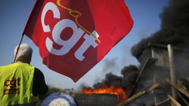 Stávkující odborář přihlíží hořící barikádě u skladu pohonných hmot