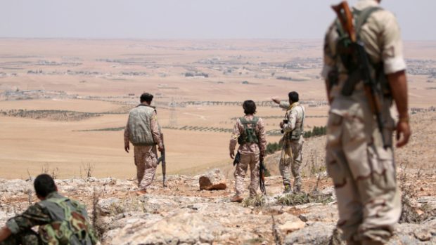 Syrští vojáci vyhlížejí ze svých pozic v Manbidži
