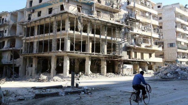 Muž projíždí na kole zničeným Aleppem