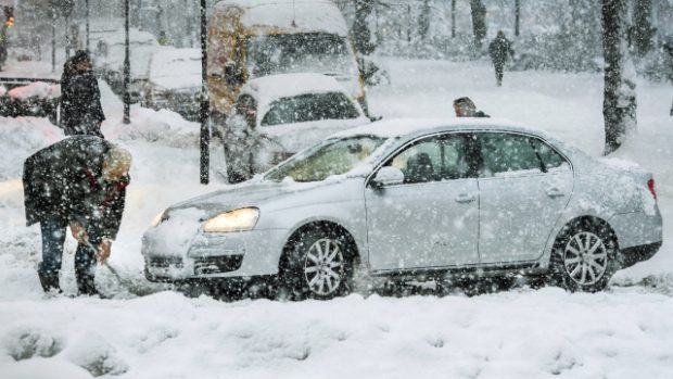 Muž ve Stockholmu odhrabává sníh okolo svého auta