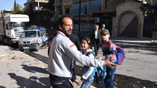 Muž evakuuje děti ze školy v západním Aleppu, kterou podle syrské televite zasáhly rakety opozice.