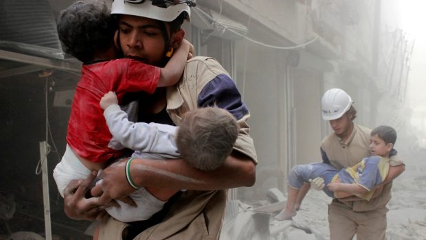 Členové civilní obrany zachraňují děti v Aleppu po leteckých náletech na město.