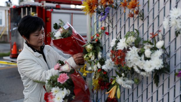 Žena pokládá květiny nedaleko místa požáru v kalifornském Oaklandu