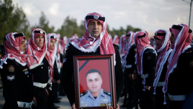 Čestná stráž drží fotografii policisty, který zahynul při teroristickém útoku v Jordánsku.