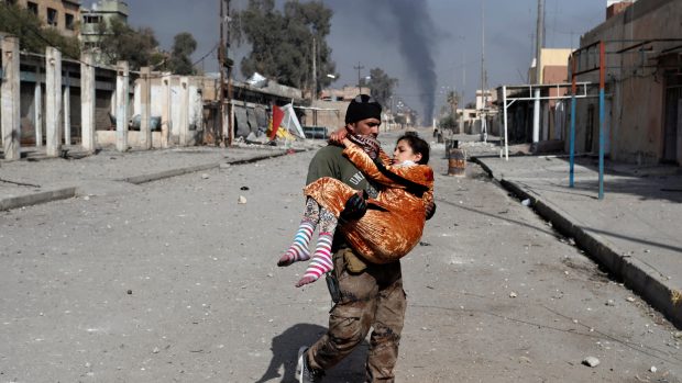 Voják zachraňuje raněnou ženu v iráckém Mosulu.