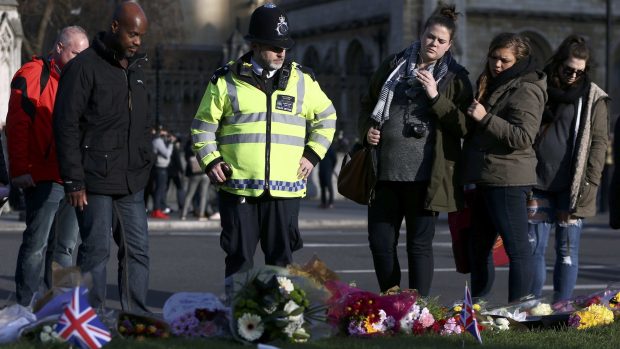 Londýn po teroristickém útoku. Policista stojí u květin na náměstí u britského parlamentu v Londýně