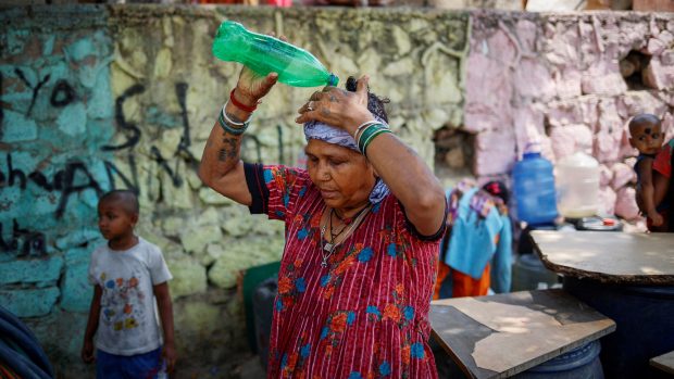 Žena si lije vodu na hlavu při teplém dni v Novém Dillí