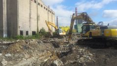 Bagry odstraňují základy dehtem kontaminovaných budov