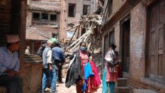 Žena ve starobylém městě Bhaktapur vynáší náruč plnou zaprášeného oblečení