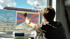 Vyvěšování tibetské vlajky v kanceláři naproti hotelu Hilton