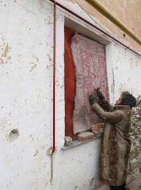 Žena izoluje okno svého bytu na předměstí východoukrajinského Slavjansku