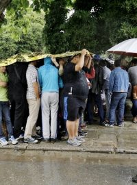 Uprchlíci se schvávají před deštěm u policejní stanice na ostrově Kos