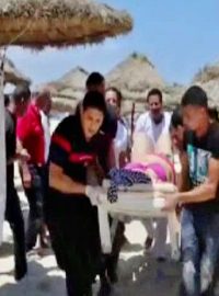 Zdravotníci na záběrech televize Tunisia TV1 odnášejí raněné z pláže po útoku atentátníka