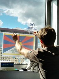 Vyvěšování tibetské vlajky v kanceláři naproti hotelu Hilton