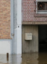 Muž vylévá vodu z domu na předměstí Villeneuve-Triage u Paříže