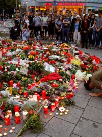 Lidé přinášejí svíčky a květiny k obchodnímu centru Olympia v Mnichově