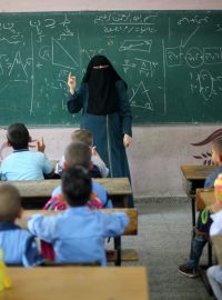 Palestinská učitelka se zahaleným obličejem vyučuje žáky ve škole v Pásmu Gazy (snímek z prvního školního dne, který tu měli už 28. srpna)