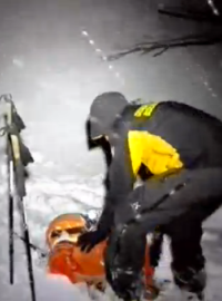 Záchranář na místě tragédie pomáhá člověku uvězněnému v závalu sněhu (snímek z amatérského videozáznamu).