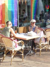Lidé mají na balkonech vyvěšené duhové vlajky hnutí za práva homosexuálů, posedávají po barech a kavárničkách.