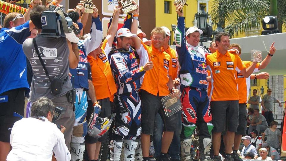 Dakar 2012: Cyril Despres z týmu KTM jako vítěz kategorie motorek uprostřed, vpravo druhý Marc Coma, za kamerou schovaný je bronzový Helder Rodrigues za Yamahu